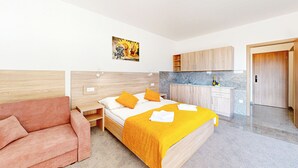 Ein modernes Hotelzimmer mit einem Bett, einer Couch, einer Küchenzeile und einer Holztür.