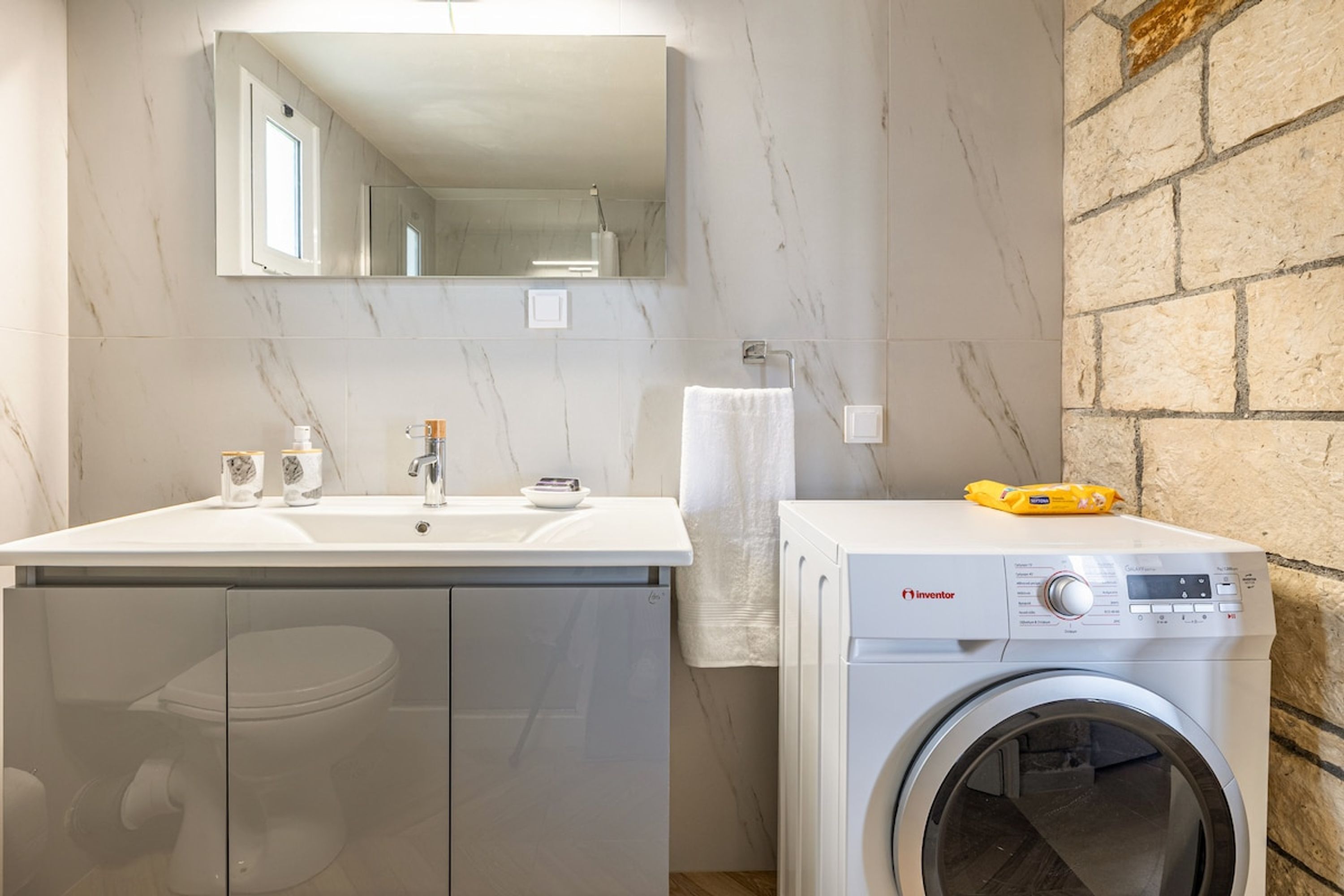 Ein Badezimmer mit Waschbecken, Spiegel, Waschmaschine und Handtuchhalter.
