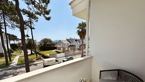 Een balkon met een tafel en stoel, met uitzicht op een straat met een bestelwagen en een gebouw op de achtergrond.