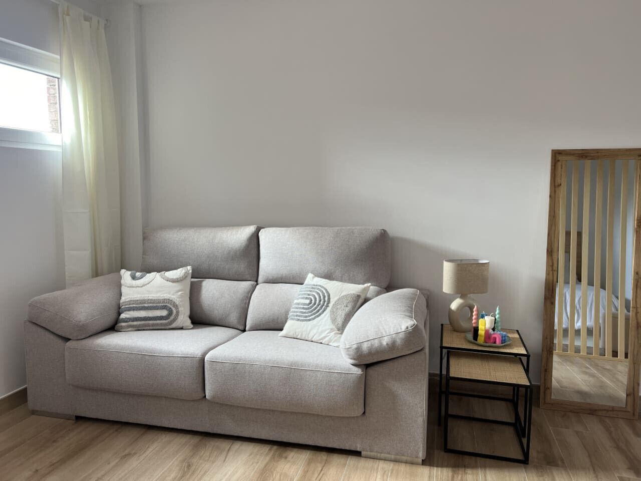 A neutral-toned sofa with a matching side table, a lamp, and a small decorative item.