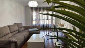 A modern living room with a sectional sofa, a coffee table, and a hanging light fixture. - Apartment in the center El Refugio 3016 (Santoña)