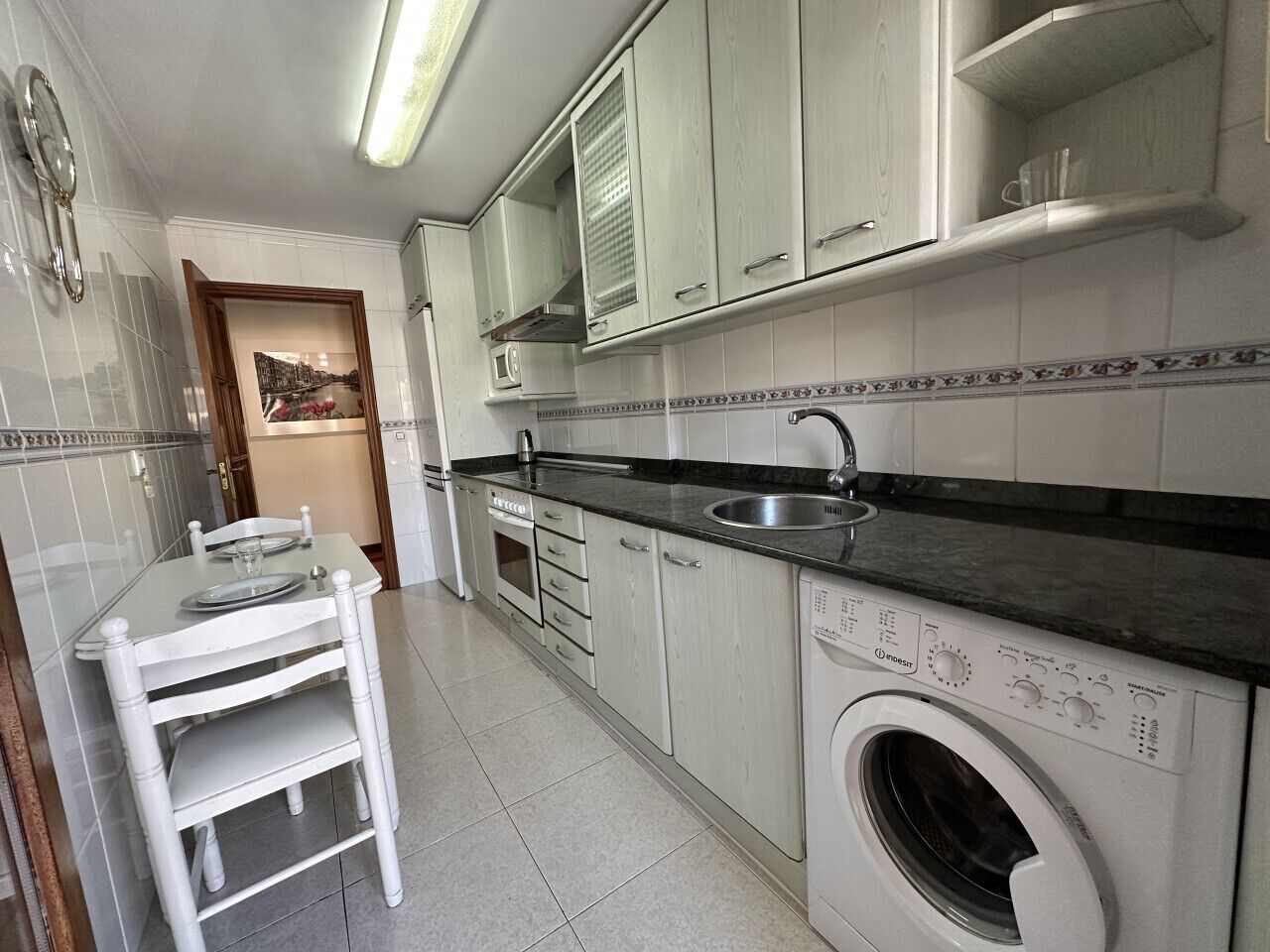 Une cuisine équipée d’un lave-linge, d’un évier et d’une table à manger avec des chaises.