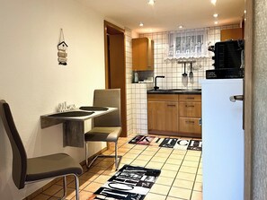 A compact kitchen with a dining area, a refrigerator, and a sink.