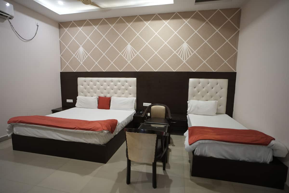 A hotel room with two beds, a desk, a chair, and a ceiling fan.