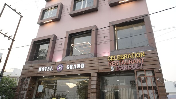 Un immeuble à plusieurs étages, sur lequel on peut lire les inscriptions « HÔTEL GRAND » et « RESTAURANT CELEBRATION ET SALLE DE BANQUET ».