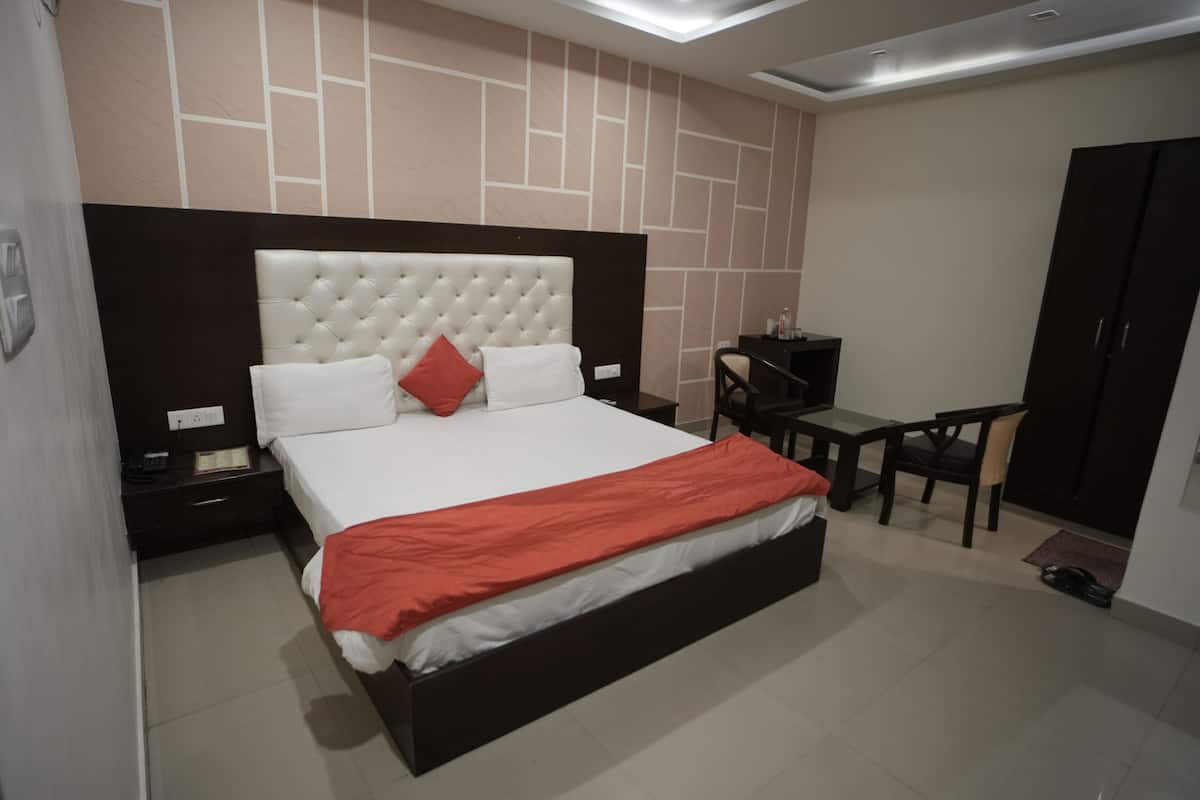 A modern bedroom with a large bed, a desk, and a wardrobe.
