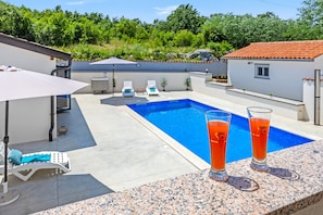 A swimming pool with lounge chairs and a table, two glasses of orange beverage, and a clear blue sky. - Nature Lovers Retreat - Casa Irena with Pool (Boljevici)