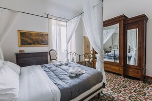 A bedroom with a bed, a wooden dresser, a mirror, and a patterned floor. - Real Umberto I by Wonderful Italy (Palermo)