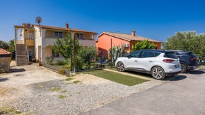 A two-story house with a driveway, parked cars, and a small garden.