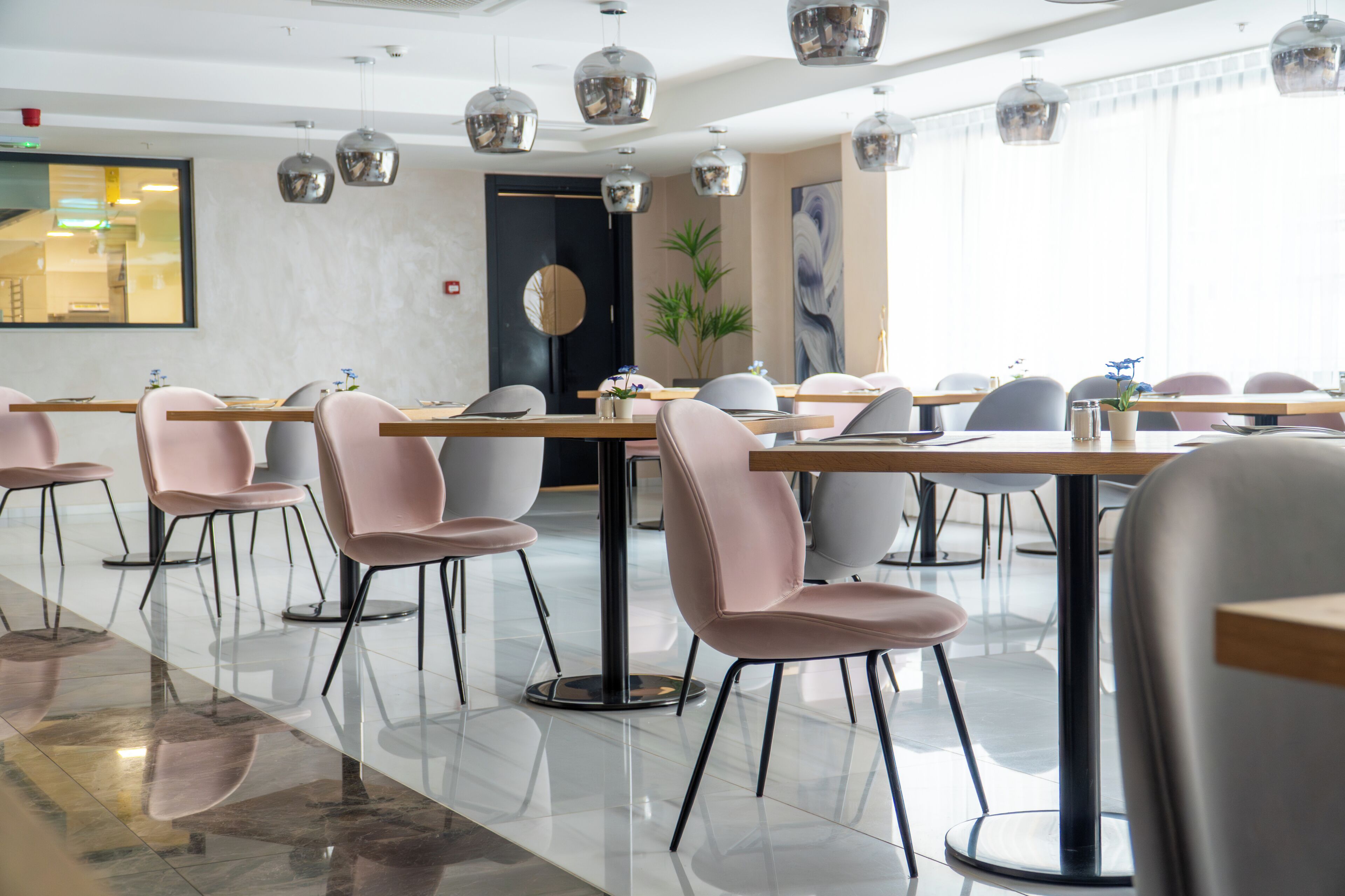 Un comedor moderno con mesas redondas, sillas e iluminación colgante.