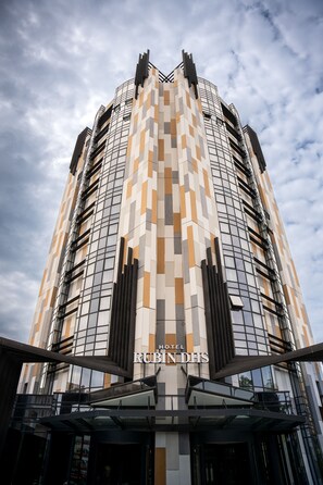 Ein modernes Hotel mit einer geometrischen Fassade, großen Fenstern und einem markanten Eingang.