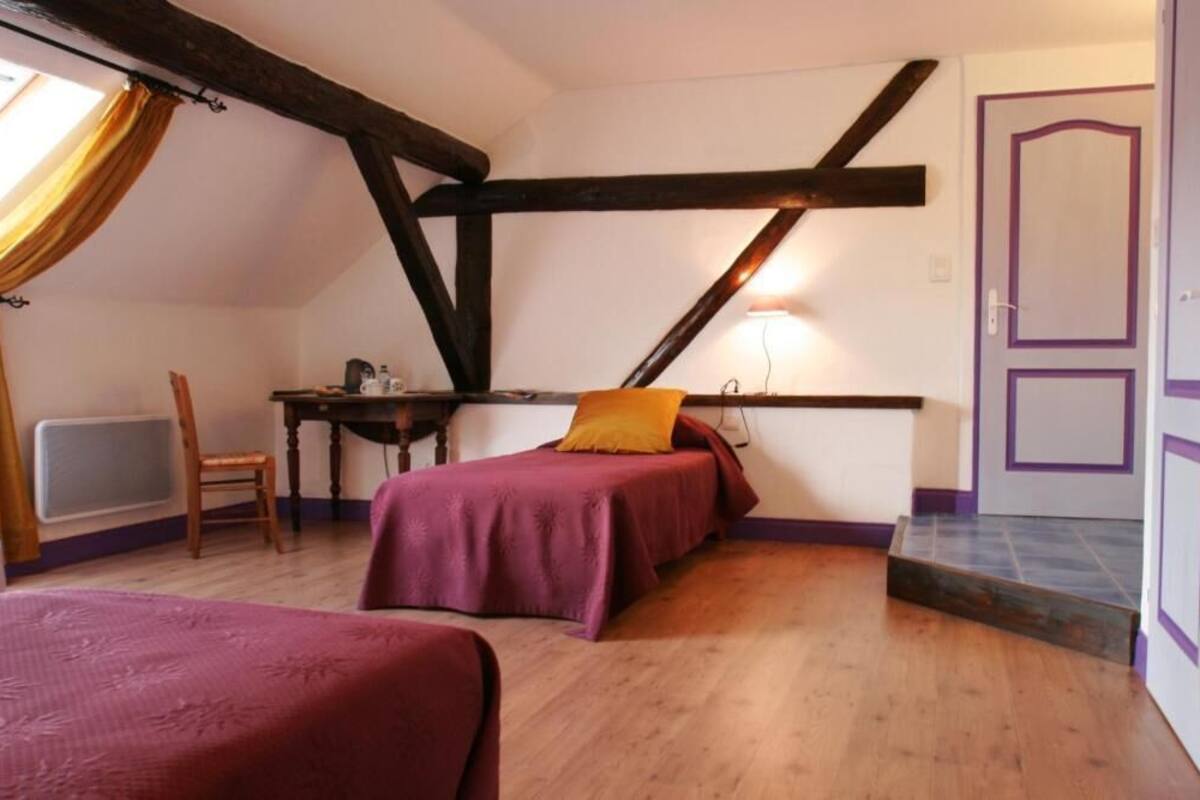 A small, cozy room with two beds, a desk, and a chair.