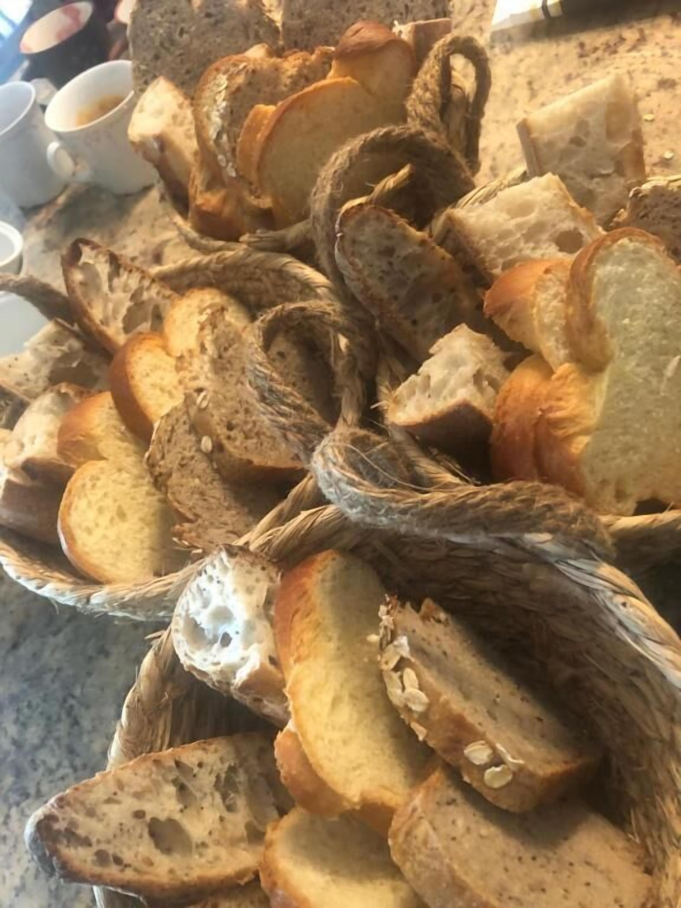A basket filled with various types of bread, including sliced and whole loaves.