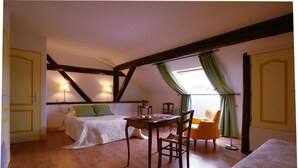 Een slaapkamer met een bed, een tafel en een stoel. Er is een raam met gordijnen.