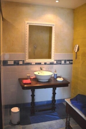 Une salle de bain avec un lavabo blanc, un miroir et un meuble-lavabo en bois.