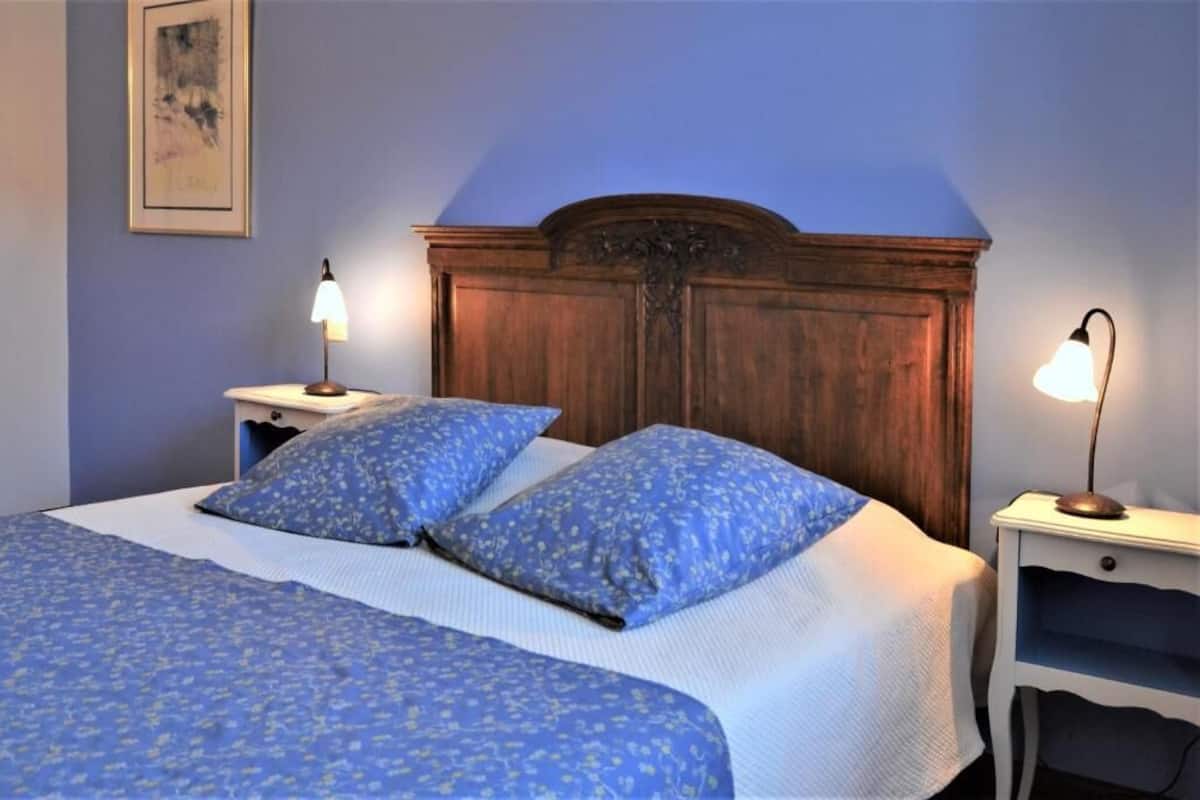 A bedroom with a bed, two nightstands, and a wooden headboard.