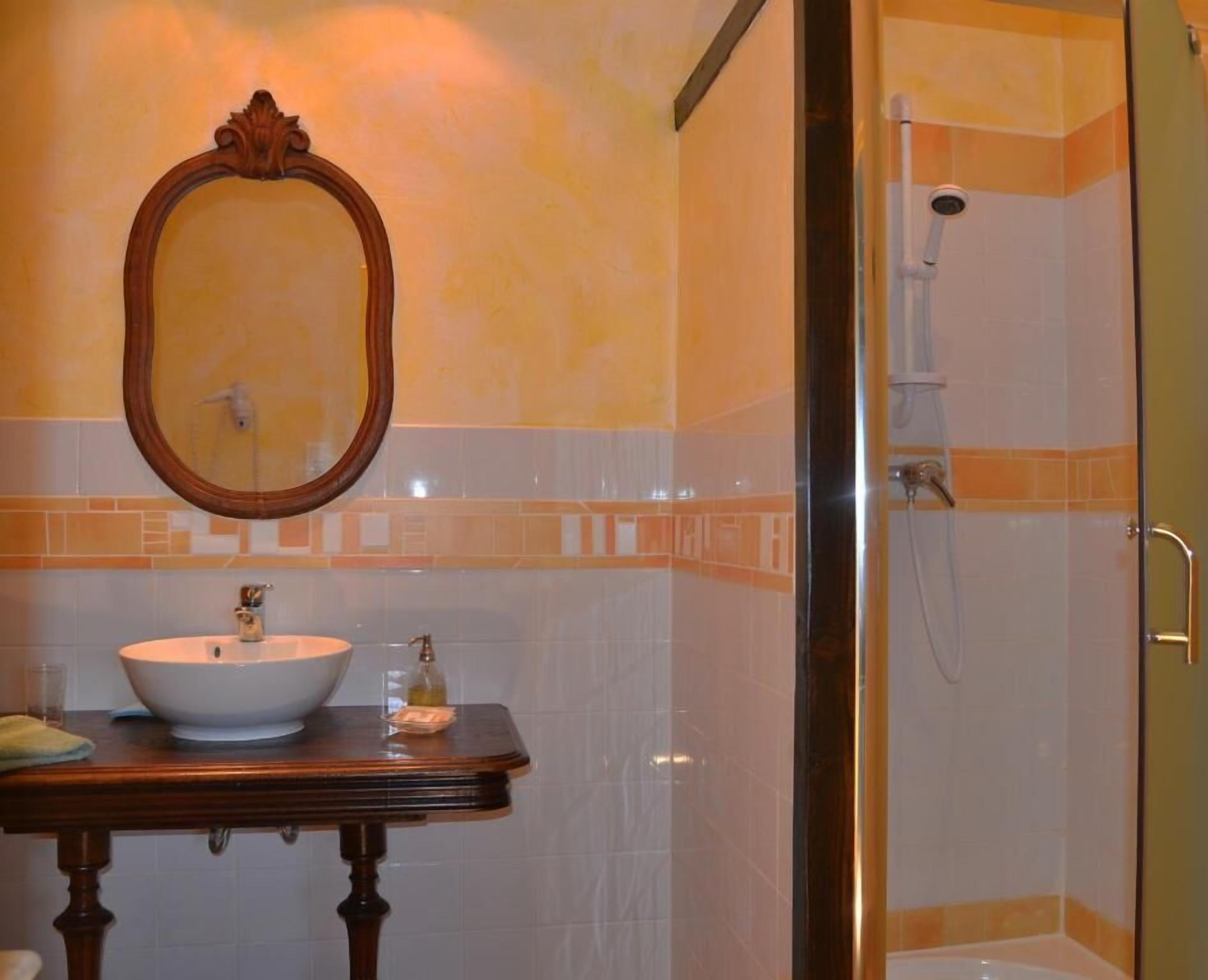 Een badkamer met een ronde spiegel, een wastafel en een douche.