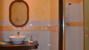 Een badkamer met een ronde spiegel, een wastafel en een douche.