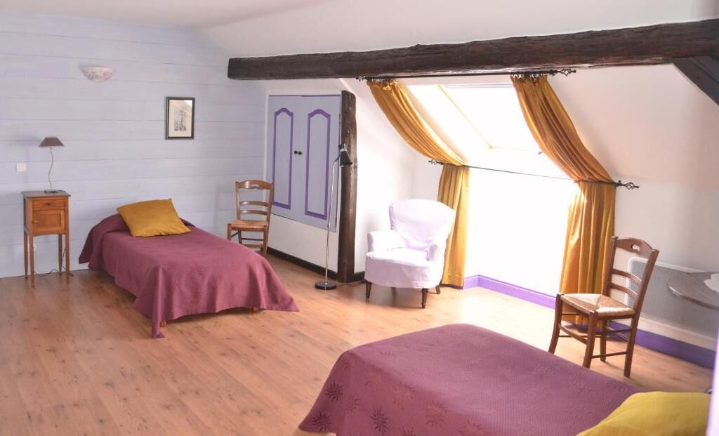 Ein Zimmer mit zwei Betten, einem Sessel, einem Kleiderschrank und einem fenster mit Vorhängen.