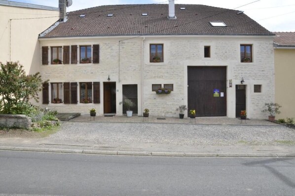 Un bâtiment à deux étages, doté d’un toit recouvert de tuiles, de nombreuses fenêtres et d’une grande porte d’entrée.