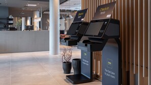 A modern hotel lobby with self-service kiosks for check-in and a fast lane to rooms. - Zleep Hotel Hamburg Volkspark (Hamburg)