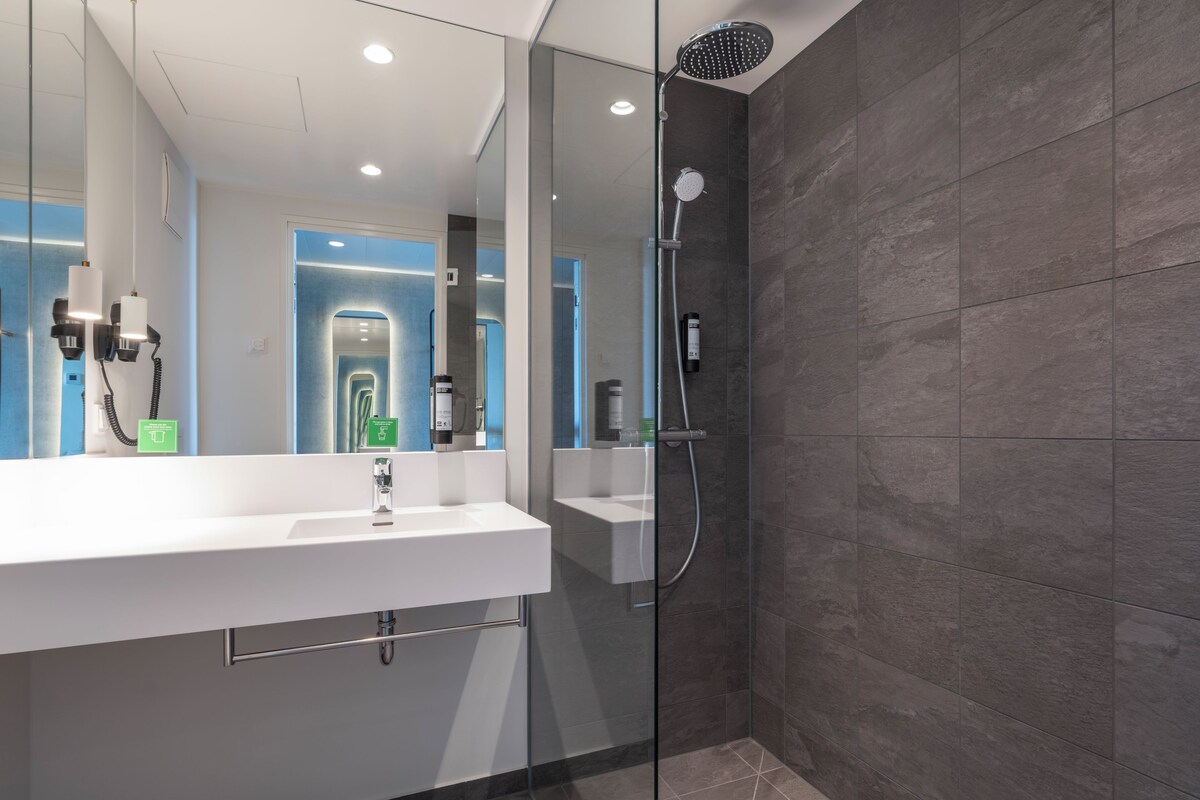 Une salle de bain moderne avec une douche à parois de verre, un lavabo blanc et un miroir.