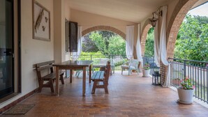 A covered patio with wooden furniture, brick flooring, and a view of greenery. - Stunning private villa with WIFI, A/C, private pool, TV, patio, pets allowed, close to San Gimignano (Montaione)