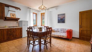 A kitchen with wooden cabinets, a dining table with chairs, a sofa, and a pendant light. - Stunning private villa with WIFI, A/C, private pool, TV, patio, pets allowed, close to San Gimignano (Montaione)