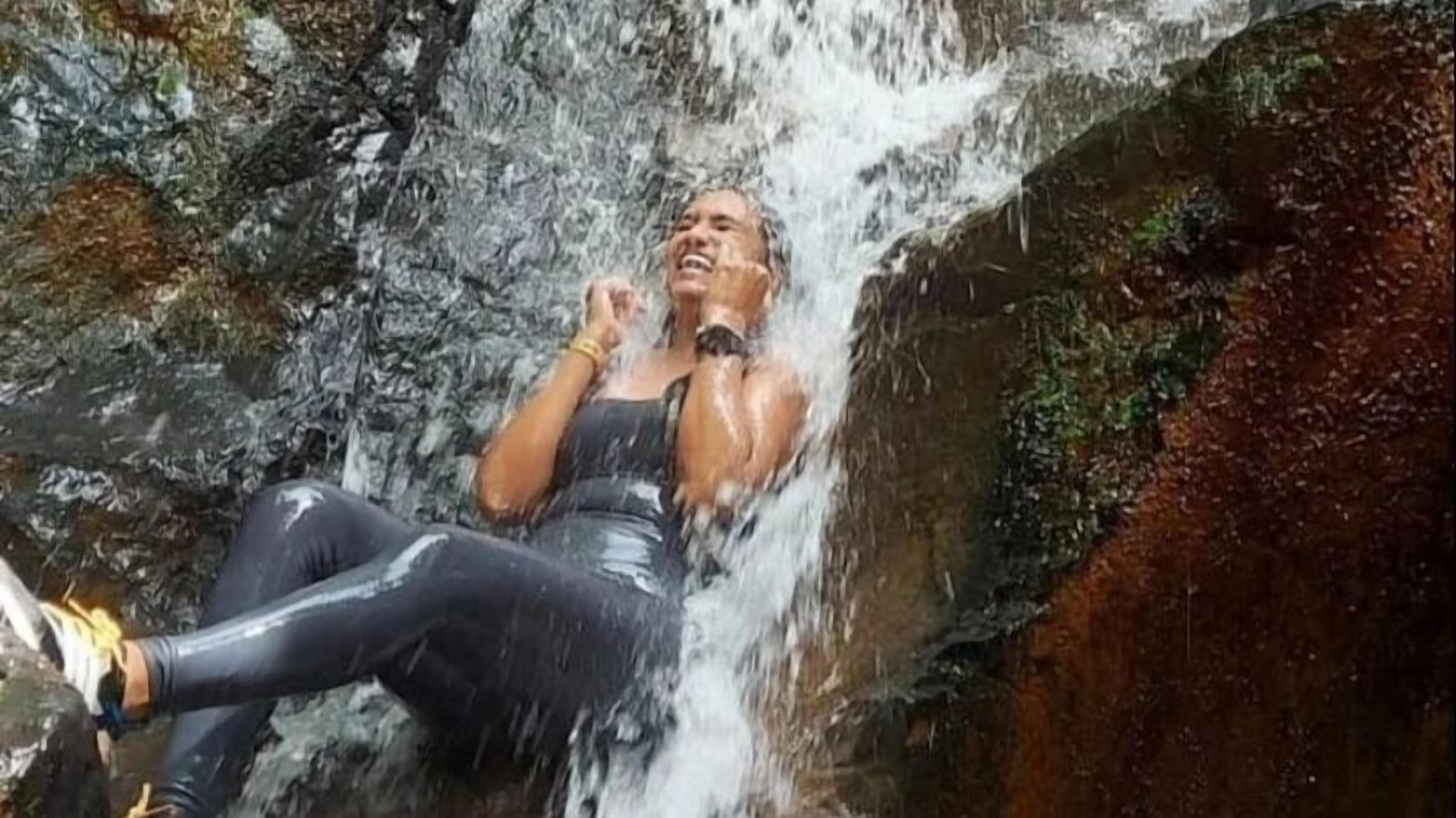 A person sitting on a rock by a waterfall.