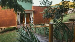 Una terraza de madera con barandilla de metal, rodeada de follaje.