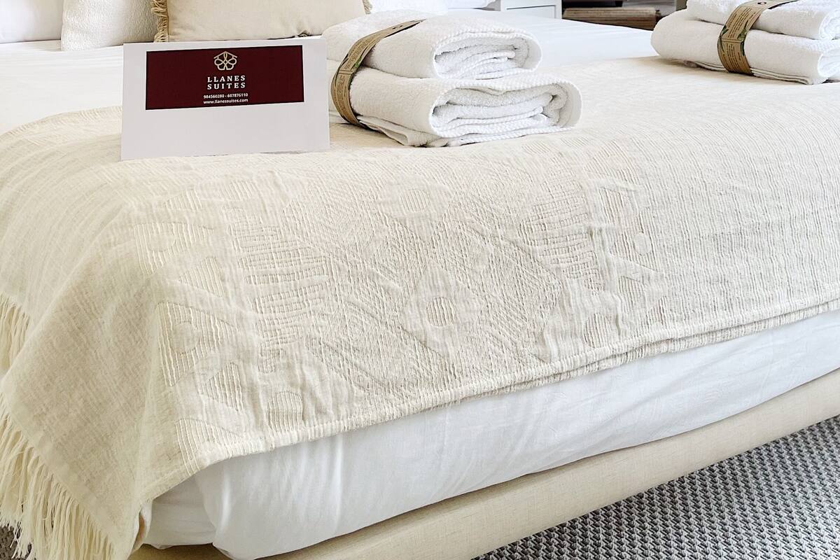 Una habitación de hotel con una cama bien hecha, un cartel que indica el nombre del hotel y vistas de la habitación contigua.