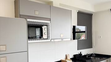 Una cocina moderna con armarios grises, encimera negra y microondas integrado.