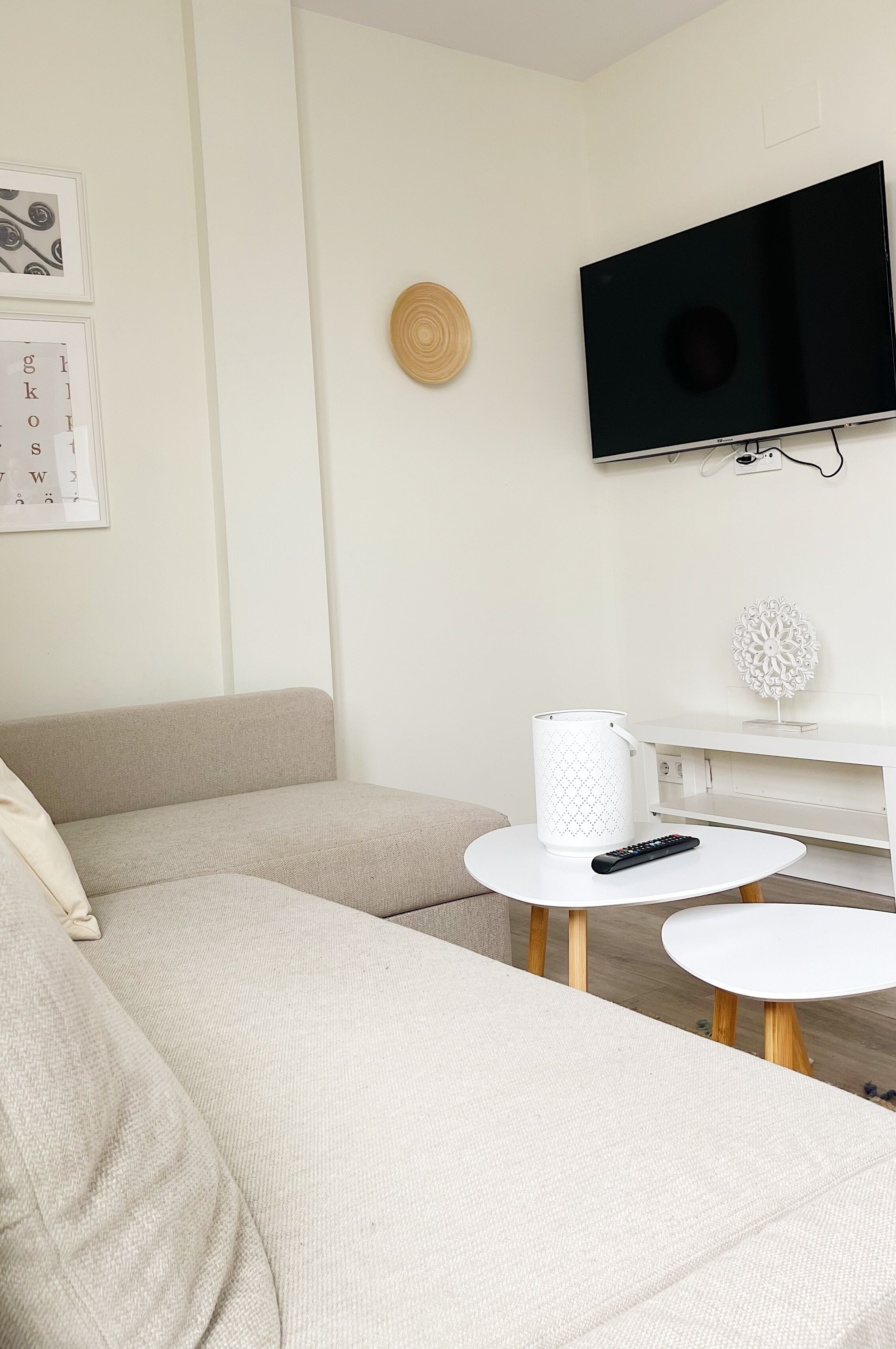 Una sala de estar con un sofá, una mesa de centro, un televisor y elementos decorativos en la pared.