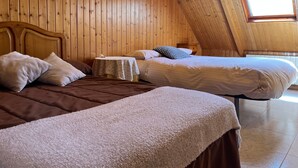 A room with wooden walls, two beds, a small table, and a window. - Holiday Home 'Los Ciegos' with Mountain View, Private Terrace and Wi-Fi (Peguerinos)