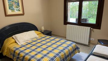 Een slaapkamer met een bed, nachtkastje, raam, radiator en een lijst aan de muur.