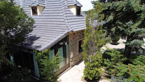 A stone building with a tiled roof, a stone pathway, and various green shrubs. - Holiday Home 'Los Ciegos' with Mountain View, Private Terrace and Wi-Fi (Peguerinos)
