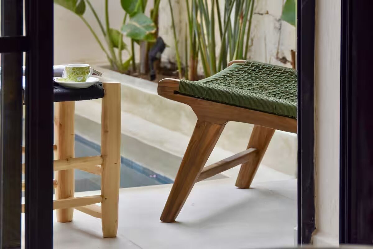 A wooden chair with a green cushion and a small table with a cup and saucer.