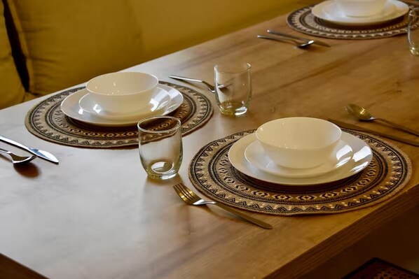 A dining table set with plates, bowls, cutlery, and a glass. - 4-Bedroom Architect-Designed Villa with Pool (Agadir)