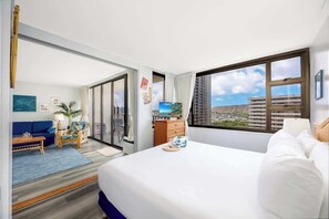 Quarto de hotel com cama, televisão, escrivaninha, cadeira, sofá e vista para a cidade.