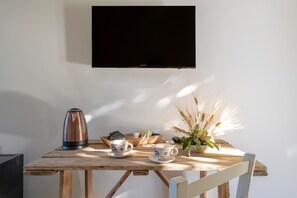 Une table en bois avec une bouilloire, deux tasses, un panier à livres et une plante.