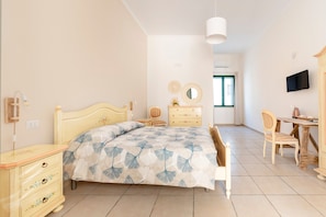 Une chambre à coucher comprenant un lit, une commode, une chaise et un bureau avec une autre chaise.