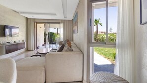 Ein modernes Wohnzimmer mit einem großen Ecksofa, einem flachbildfernseher an der Wand und einem Essbereich mit Tisch und Stühlen.