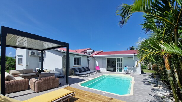 A poolside area with lounge chairs, a covered seating area, and a pool.