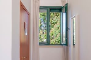 Une pièce avec une porte, une fenêtre donnant sur des arbres et un rideau.