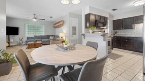 Une cuisine moderne avec des meubles de couleur sombre, un four à micro-ondes et une cuisinière. On y trouve également un coin repas avec une table ronde et des chaises.