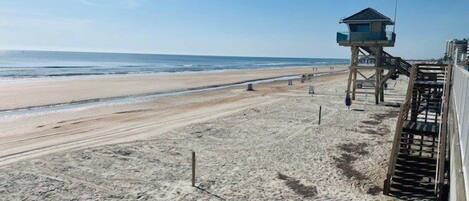 Una playa con una torre de salvavidas y una estructura de madera con escaleras.