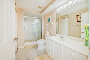 Un bagno con cabina doccia in vetro, un water bianco, un mobile lavabo con specchio e un lavandino.