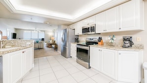 A modern kitchen with white cabinetry, stainless steel appliances, and a granite countertop.