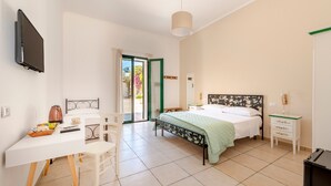 Une chambre à coucher comprenant un lit, une table de chevet, une chaise, un bureau et un téléviseur fixé au mur.