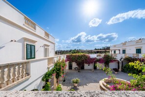 A courtyard with white buildings, green shutters, and flowering plants.